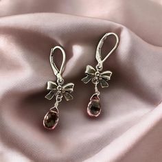 Add a touch of fun and elegance to your outfit with these stunning sterling silver earrings featuring a briolette cut pink tourmaline and a charming bow tie ribbon design. The lever back closure ensures a secure fit, while the earrings hang elegantly at 1 inch in length. Bow Tie Ribbon, Tie Ribbon, Ribbon Design, Pink Tourmaline, Bow Tie, Sterling Silver Earrings, Tourmaline, Jewelry Earrings Dangle, 1 Inch