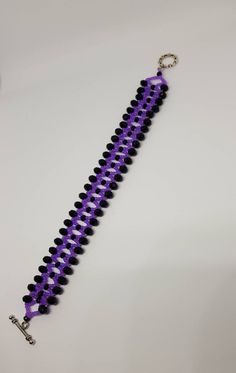 a purple and black beaded bracelet on a white surface