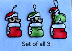 three cross stitch christmas ornament hangings on a blue background with the words set of all 3