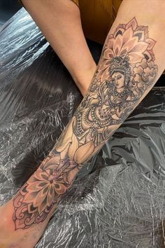 a woman's leg with a tattoo on it and flowers in the middle of her legs