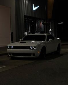 a white sports car parked in front of a building at night with the moon behind it