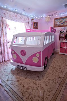 a pink and white vw bus bed in a room with curtains on the windows