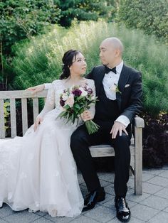 a bride and groom are sitting on a bench