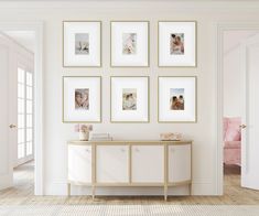 a white room with framed pictures on the wall and a table in front of it