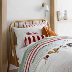 a bed with white sheets and red and green striped pillows