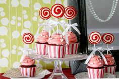 some cupcakes are on a cake stand with red and white frosted decorations