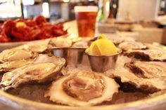 oysters on the half shell with a lemon wedge and a glass of beer in the background