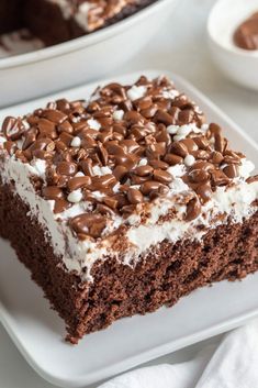 a piece of chocolate cake with white frosting and sprinkles on top