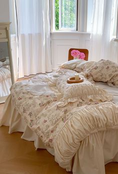 a bed with ruffled bedspread and pillows in front of a large window