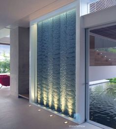 the inside of a modern house with large glass windows and water feature on the wall