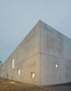 the building is made out of concrete and has two windows on each side that are lit up at night