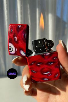 a hand holding a red lighter with eyes on it