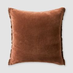 a brown velvet pillow with fringe trim