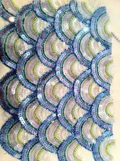 several pieces of blue and green sequins on a white tablecloth with words written in chinese