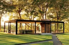 a glass house in the middle of a grassy area with trees and grass around it