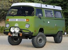 a green vw bus parked in front of some trees