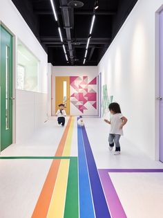 two children are standing in the middle of a room with rainbow painted on the floor