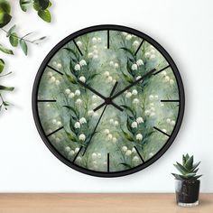 a clock with flowers painted on it sitting next to a potted plant and wall