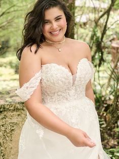 a woman in a wedding dress posing for the camera with her hand on her hip