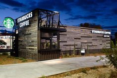 a starbucks coffee shop is lit up at night with the sky in the back ground