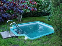 an above ground swimming pool in the middle of a yard with green grass and purple flowers