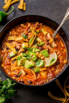 a black bowl filled with chili, beans and avocado