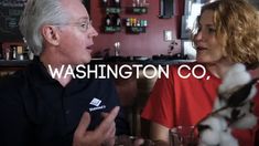 two people sitting at a table talking to each other with the words washington co in front of them