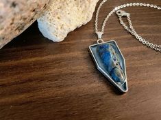 This beautiful handmade, one-of-a-kind silver pendant with a real Blue Apatite Stone accent is perfect for dressing up or down. This pendant has approximately a height of 2 in. x 1 in. in length and is made from a durable silver metal alloy, and stone set in blue mica tinted resin. Artisan Apatite Jewelry For Gifts, Unique Blue Rectangular Pendant Jewelry, Silver Kyanite Jewelry As Gift, Handmade Blue Apatite Necklace, Nickel-free Apatite Dangle Jewelry, Silver Kyanite Jewelry For Gift, Blue Apatite Pendant Jewelry, Blue Sodalite Pendant Necklace, Apatite Stone