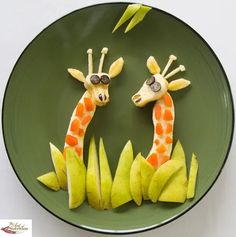 two giraffes made out of fruit on a green plate with lightning in the background