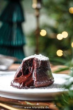 a piece of chocolate cake sitting on top of a white plate next to a christmas tree