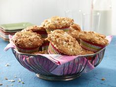 some muffins are sitting in a bowl on a table next to a glass of milk