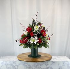 a bouquet of red roses and white orchids in a green vase on a marble slab