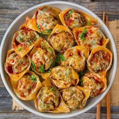 a white bowl filled with stuffed shells on top of a wooden table next to chopsticks