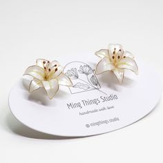 Embrace the elegance of nature with these stunning handmade earrings, inspired by the delicate beauty of lily flowers. Each earring captures the grace and sophistication of lilies, renowned for their classic charm and timeless appeal. Lilies are often associated with purity, renewal, and refined beauty, making them a perfect symbol for grace and elegance. Meticulously crafted, these earrings feature high-quality gold-plated posts and wire, paired with UV resin and colorant to achieve a refined, Elegant White Earrings With Pressed Flowers, Delicate Flower Earrings With 3d Flowers As Gift, Delicate 3d Flower Earrings As Gift, Delicate White Earrings With Pressed Flowers, White Earrings With Pressed Flowers As Gift, White Earrings With Pressed Flowers For Gift, White Pressed Flower Earrings For Wedding, White Flower Earrings With Pressed Flowers For Wedding, White Birth Flower Drop Earrings