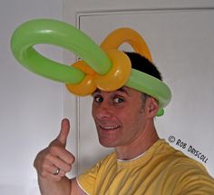 a man in a yellow shirt is holding two green and yellow rings on his head