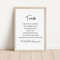 a white framed poster with the words teach in cursive writing, on a wooden floor