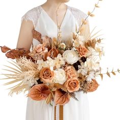 a woman in a white dress holding a bouquet of orange and white flowers on her arm