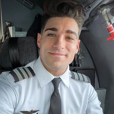 a man wearing a pilot's uniform sitting in the back seat of a plane