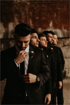 a group of men standing next to each other wearing suits and bow ties on their lapels