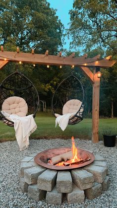 an outdoor fire pit with hanging chairs and lights