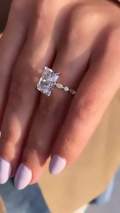 a close up of a person's hand with a diamond ring on their finger