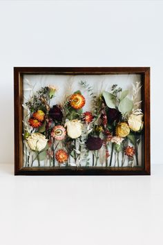 an arrangement of flowers in a wooden frame