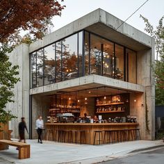 an outdoor bar with wooden tables and stools on the sidewalk next to a building