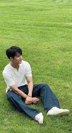 a man sitting in the grass with his hands on his knees