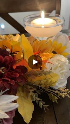 a candle that is on top of a table with flowers in front of the candles