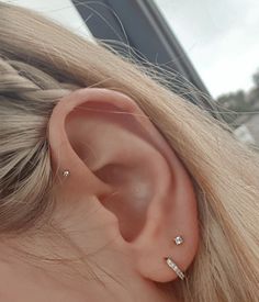 a close up of a person's ear with three small diamond studs on it