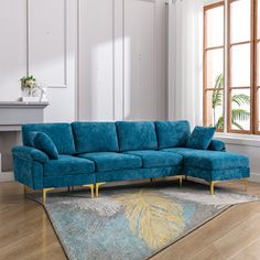 a blue couch sitting on top of a wooden floor next to a window in a living room