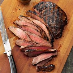 sliced steak on cutting board with knife next to it