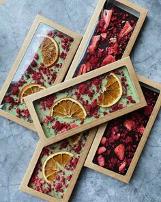 three wooden trays filled with orange slices and cranberries