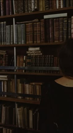 a woman standing in front of a bookshelf filled with lots of old books